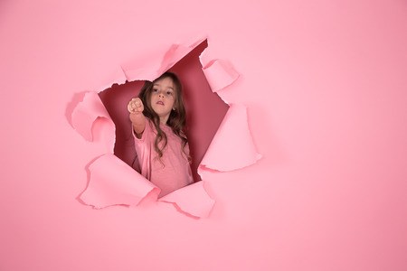 little girl with long hair playing superhero on pink background, girl power conceptの写真素材