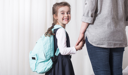 Parent and elementary school student go hand in hand on a light background . Back to school conceptの写真素材