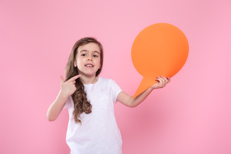 Cute little girl with speech icon on pink background .The concept of communication and communication . Studio shootingの写真素材