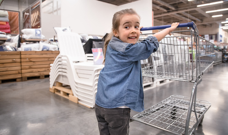 Mother and daughter in blue shirts shopping in supermarket using cartの写真素材