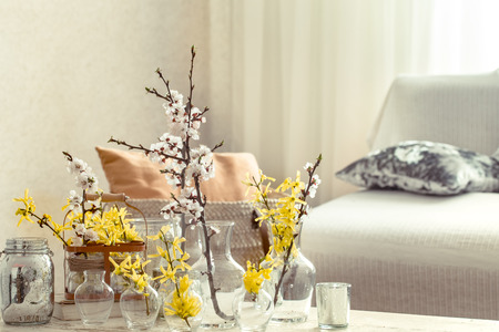 Still-life. Home cozy beautiful decor in the living room, vases with spring flowers, on the background of a wooden table, interior detailsの写真素材