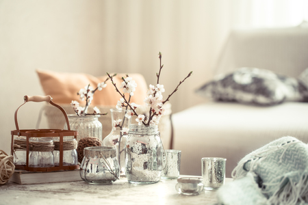 Still-life. Home cozy beautiful decor in the living room, vases with spring flowers, on the background of a wooden table, interior detailsの写真素材