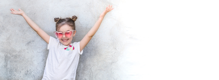Outdoor portrait little girls with sunglasses. Gray textured wall background, copy space.の写真素材