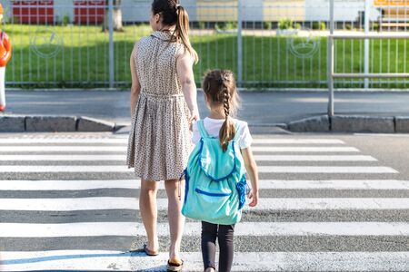 Back to school education concept with girl kids, elementary students, carrying backpacks going to class on school first day holding hand in hand together walking up building stair happilyの写真素材