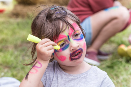 smiling girl with face art painting like tiger, little boy making face painting, halloween party,...