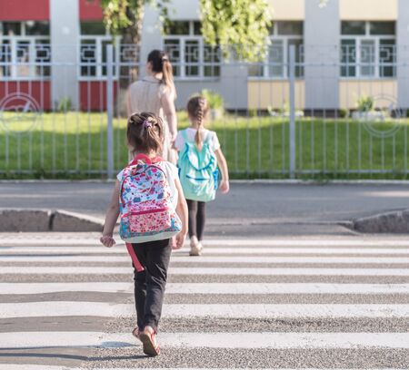 Back to school education concept with girl kids, elementary students, carrying backpacks going to class on school first day holding hand in hand together walking up building stair happilyの写真素材