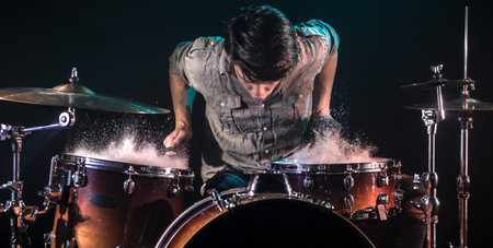 musician playing drums with splashes, black background with beautiful soft light, emotional play,...