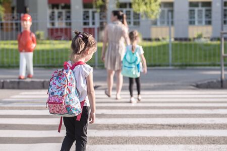 Back to school education concept with girl kids, elementary students, carrying backpacks going to class on school first day holding hand in hand together walking up building stair happilyの写真素材