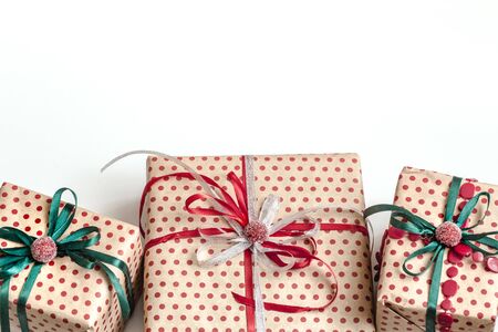 Christmas composition of various gift boxes wrapped in craft paper and decorated with satin red and green ribbons. Top view, flat lay, place for text. White background.の写真素材