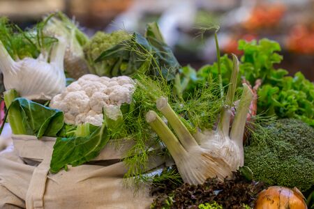 Display of fresh ripe organic broccoli, salad with greens and vegetables in cotton bag at the weekend farmer's market with blurred backgroundの写真素材