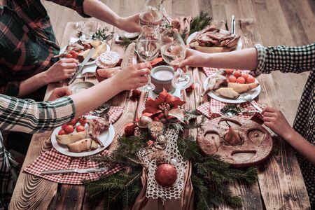 Flat-lay of friends hands eating and drinking together. Top view of people having party, gathering, celebrating together at wooden rustic table set with different wine snacks and finger foodsの写真素材