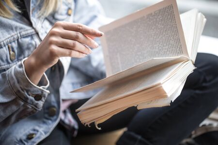 Young girl sitting in cozy cafe and reading a bookの写真素材