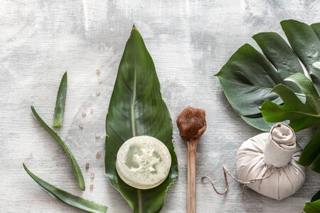 Flat-lay natural cosmetics and accessories with tropical leaves to cleanse the skin. Basic hygiene and body care items on white background, copy space.の写真素材