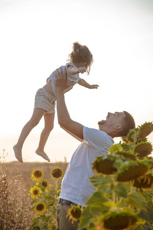 Happy family, dad with a little daughter playing in the field at sunset. The concept of family values and friendship.の写真素材