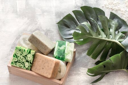 Flat-lay natural beautiful cosmetics handmade soap with tropical leaves on a light background, top viewの写真素材