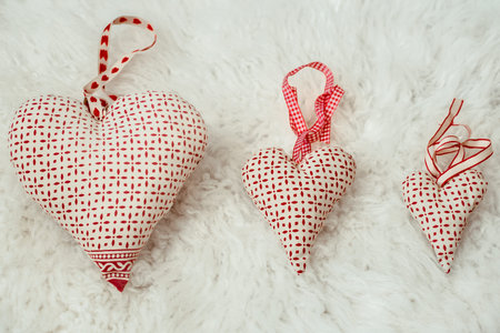 Hearts made of fabric of different sizes handmade on a fluffy light plaid . top view. The concept of...