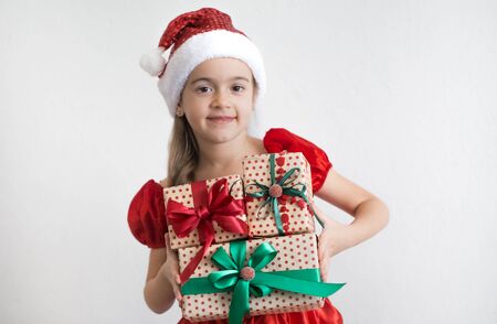 portrait of a little girl dressed in Christmas costume with gifts on a light background. Festive concert.の写真素材