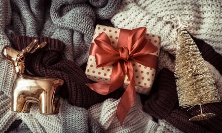 Christmas background with cozy sweaters and festive decor box with red bow. Top view.の写真素材
