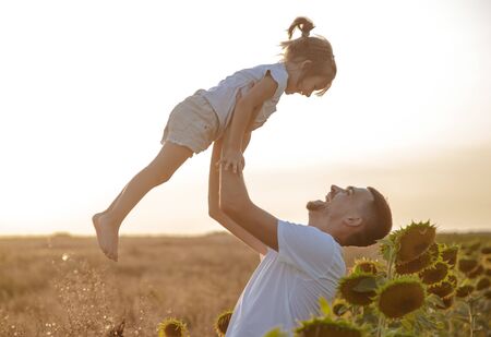 Happy family, dad with a little daughter playing in the field at sunset. The concept of family values and friendship.の写真素材