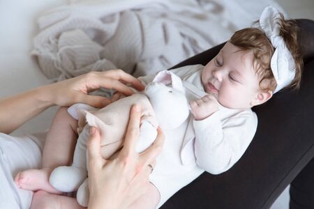 Mom plays with a toy with her newborn daughter, lying on the bed, top view. The concept of motherhood and child development.の写真素材