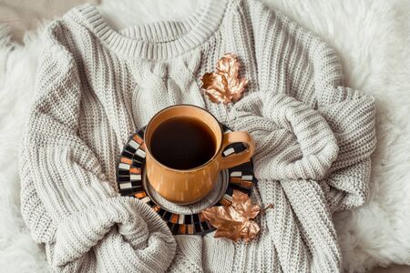 Still life with gold leaves and a yellow large Cup of tea wrapped snugly in a sweater . The concept of the autumn mood . Top view.の写真素材