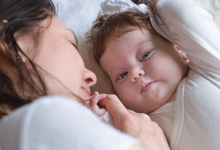 Mom lies with a newborn baby, top view. Close up. The concept of motherhood and child development.の写真素材