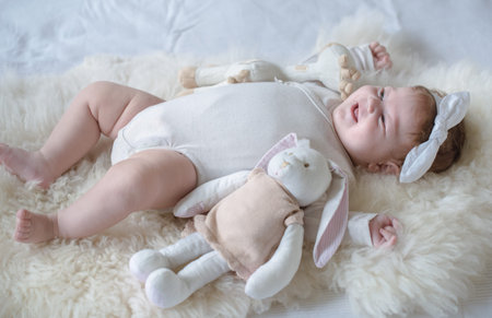 Portrait of newborn cute girl with soft toys lying on bed, top view. The concept of motherhood and child development.の写真素材