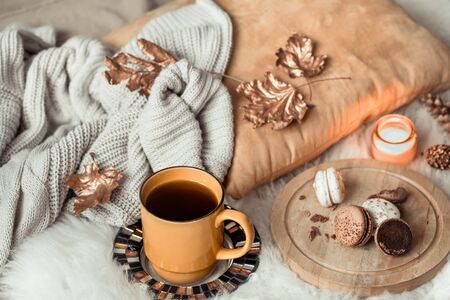 Still life yellow large Cup of tea and dessert macaroon, in the autumn interior with autumn leaves and a cozy sweater . The concept of the autumn mood .の写真素材