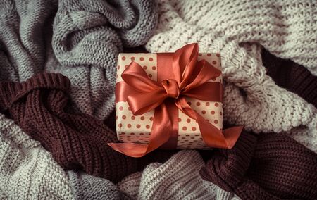 Christmas background with cozy sweaters and festive decor box with red bow . Top view.の写真素材