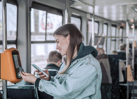 A young woman contactless pays for public transport. Payment by card, Bank transfer .