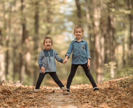 two lovely sisters walk in the autumn forest holding hands. The concept of friendship and care....