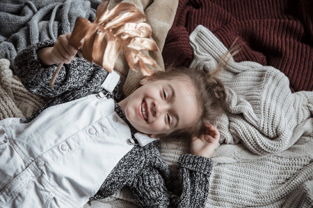 Portrait of a cute little girl in a sweater with a gold leaf in her hands. Lies in the background of...