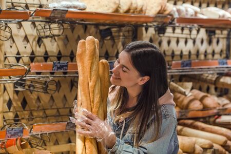 Only the best and fresh bakery. Young woman in supermarket with fresh bread . Health food. Healthy food, organic products.の写真素材