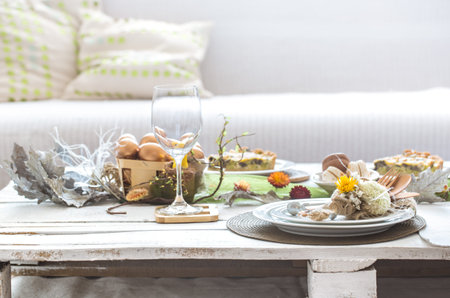 The interior of the room with a festive Easter table .A large white wooden table with a festive cake...