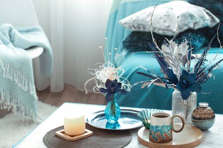 Modern living room, with artificial flowers in a vase and home decor items on a wooden light table.の写真素材