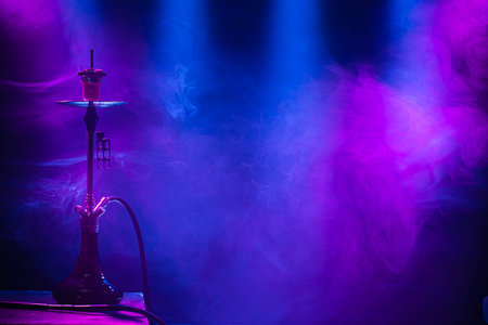The classic hookah. Beautiful background, with colored rays of light and smoke. The concept of...