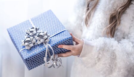 A little girl is holding a blue holiday gift . Concept of holidays.の写真素材