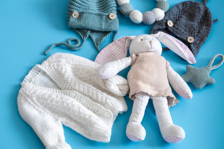 Knitted baby clothes and accessories on a blue background . The view from the top