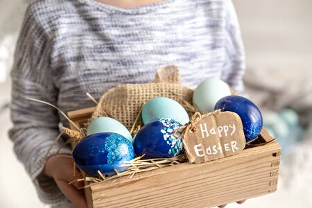 A little girl is holding a basket of Easter eggs . close up . The concept of the Easter holiday.の写真素材