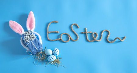 Easter creative inscription on a blue background with items of Easter decor. The concept of the...