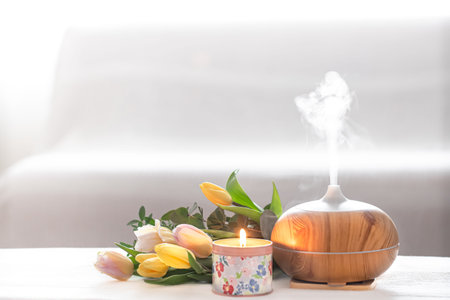 Aromatic oil diffuser lamp on the table on a blurred background with a beautiful spring bouquet of...