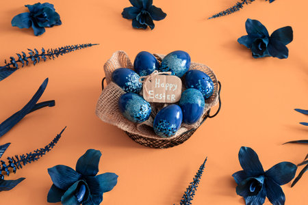 Creative Easter layout made of colorful eggs and flowers on blue background. Circle wreath flat lay...