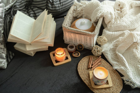 Still life cozy house with decorative details in the interior . Household items and comfort. Candles and a book lie on the bed in the living room.の写真素材