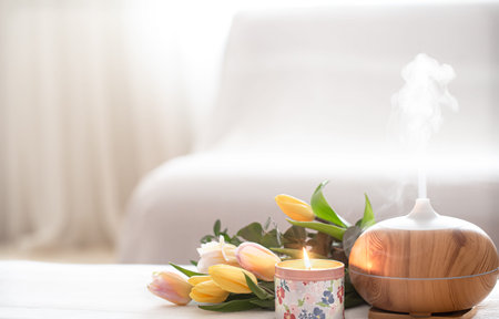 Aromatic oil diffuser lamp on the table on a blurred background with a beautiful spring bouquet of...