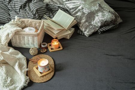 Still life cozy house with decorative details in the interior . Household items and comfort. Candles and a book lie on the bed in the living room.の写真素材