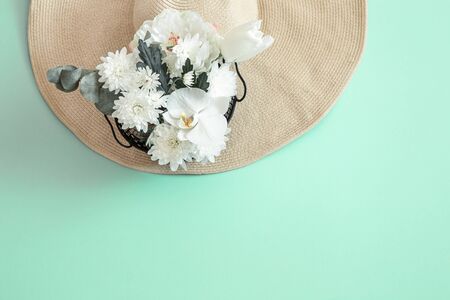 Summer background with white fresh flowers and a large wicker hat, on a solid background. Summer concept.の写真素材