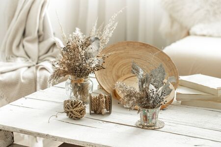 Decorative items in the cozy interior of the room , a vase with dried flowers on a light wooden table.の写真素材