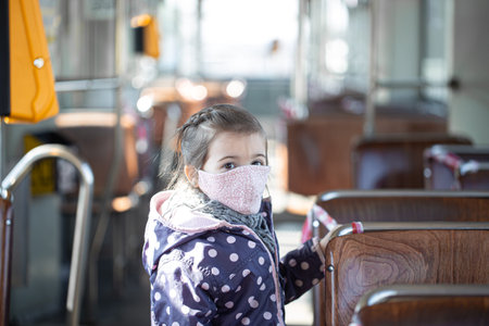 A little girl in an empty public transport during the pandemic. Coronavirus.の写真素材