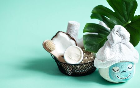 Creative Spa concept .Coconut with a face mask and towel on top . On a blue background with body care items .の写真素材