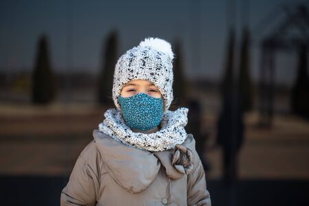 Coronavirus concept .A little girl wears a mask on her face during a virus epidemicの写真素材